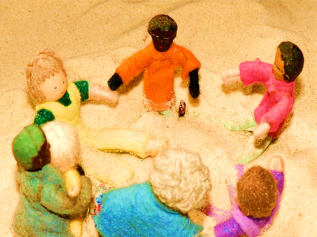 Circle of toy figures in sand tray